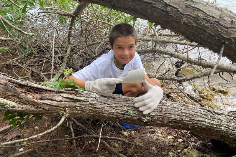 Logan collects trash under the trees