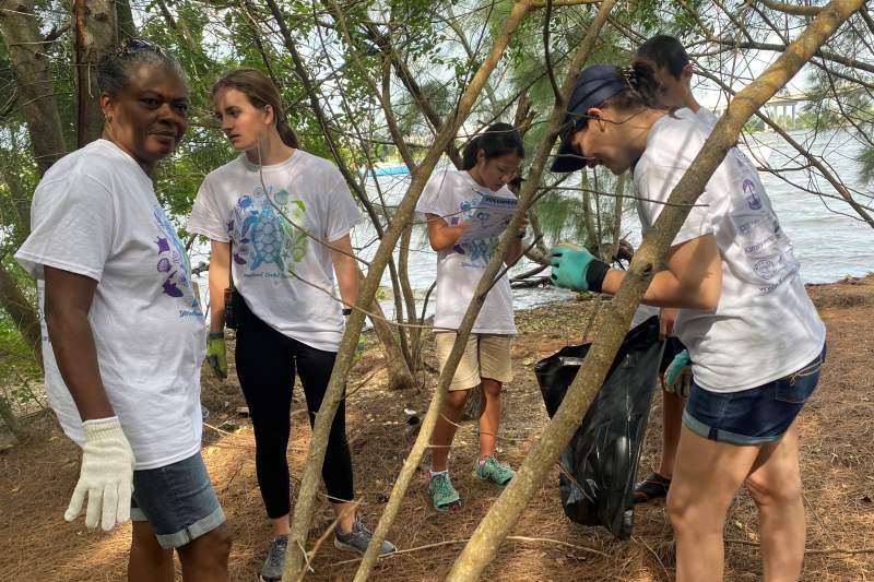 Team members and parents collect trash on a spoil island