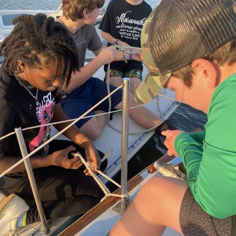 Xana practices a cleat knot with Ezra looking on