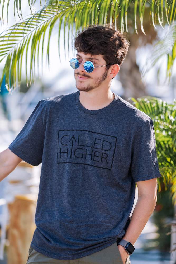 Male in a grey and black Called Higher Adventures T-shirt