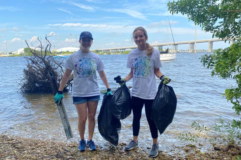 Megan and Sarah carry bags with trash collected